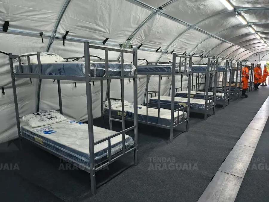 Dormitório dentro da tenda carpa, com beliches organizados