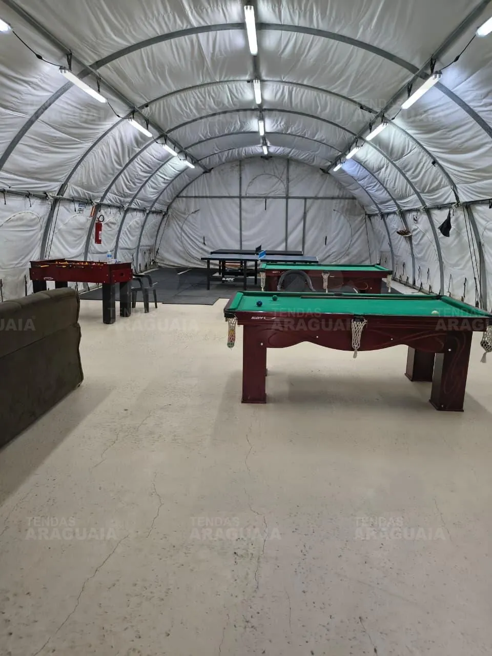 Sala de jogos com sinuca, pebolim e ping pong dentro da tenda carpa